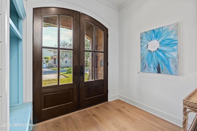 foyer entrance with french doors, light hardwood / wood-style floors, plenty of natural light, and ornamental molding