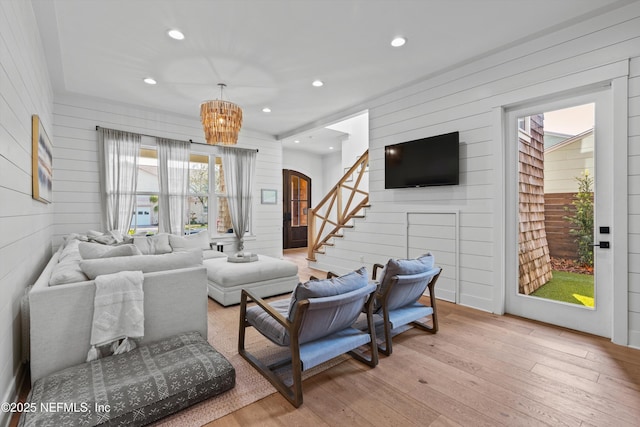 living room with a notable chandelier, wood walls, and light wood-type flooring