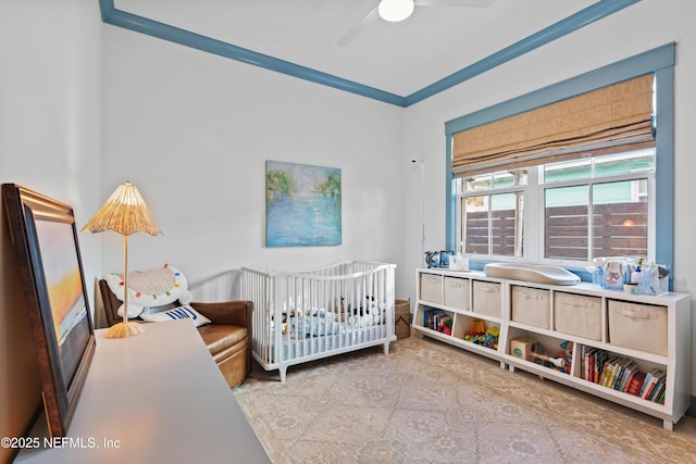 bedroom with ceiling fan, a crib, and ornamental molding