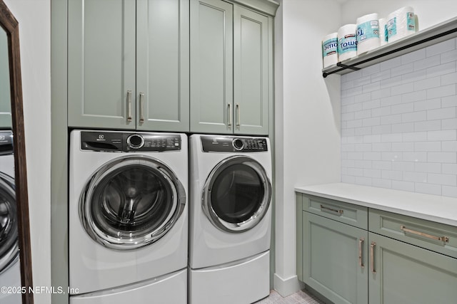 clothes washing area with washing machine and dryer and cabinets