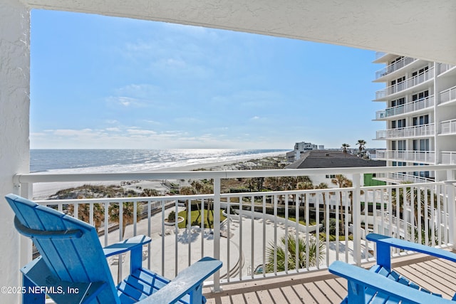 balcony with a water view and a view of the beach