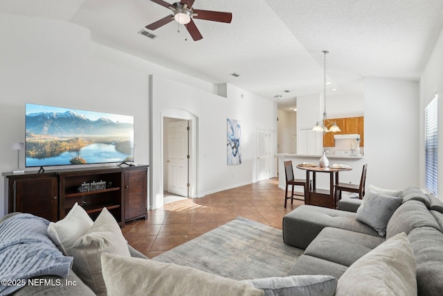 living room featuring ceiling fan, light tile patterned floors, a textured ceiling, and vaulted ceiling