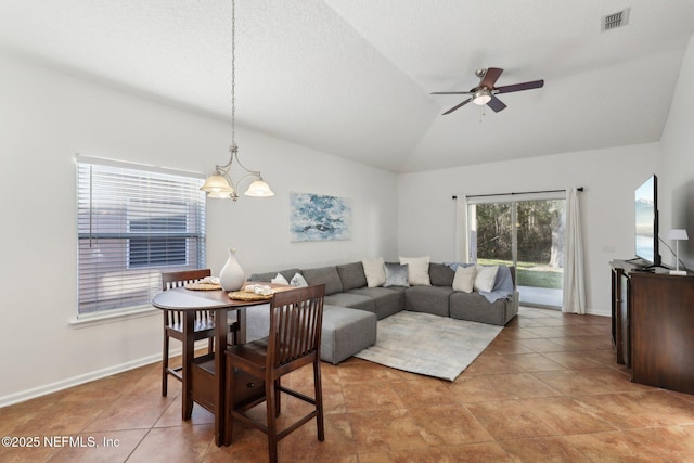 tiled living room with ceiling fan with notable chandelier and lofted ceiling