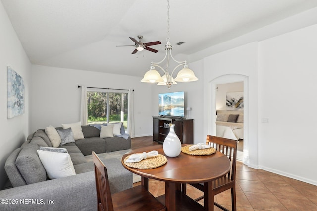 dining space featuring ceiling fan with notable chandelier, tile patterned floors, and vaulted ceiling