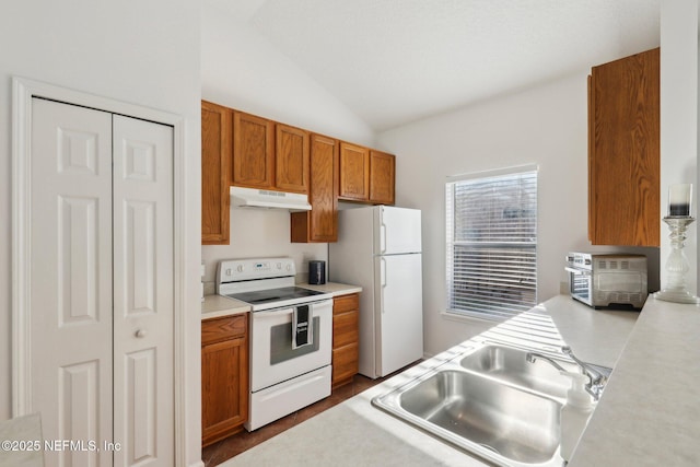 kitchen with lofted ceiling, white appliances, and sink