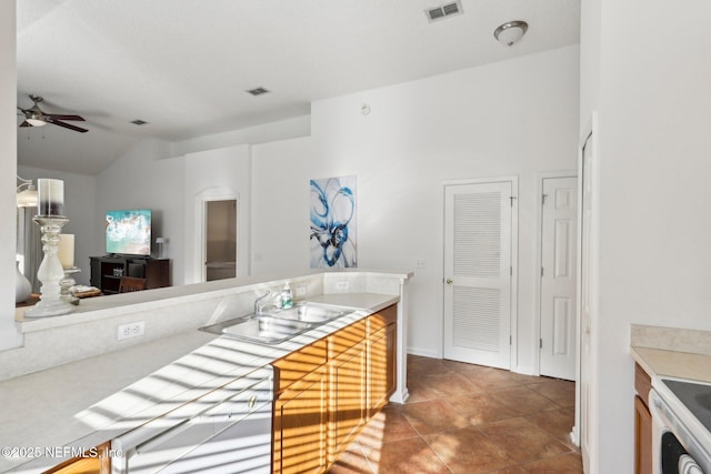 kitchen featuring range, ceiling fan, lofted ceiling, and sink