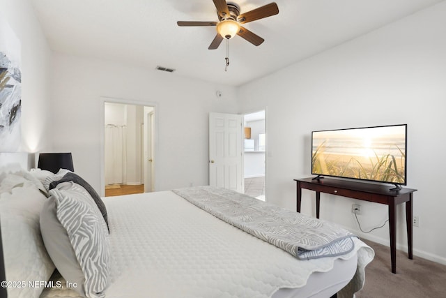 carpeted bedroom with ensuite bathroom and ceiling fan