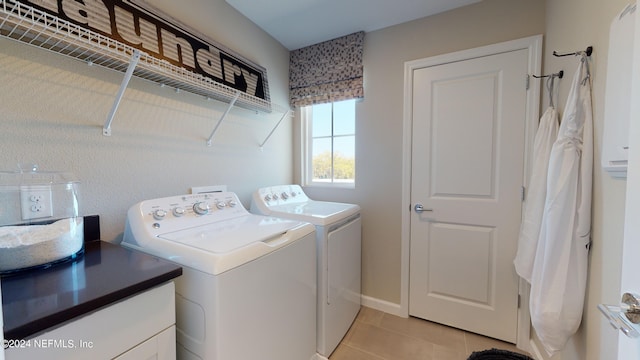 clothes washing area with washer and clothes dryer and light tile patterned floors