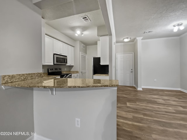 kitchen with light stone countertops, stainless steel appliances, kitchen peninsula, a textured ceiling, and white cabinets