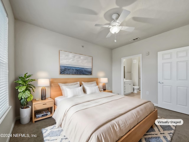 bedroom featuring dark colored carpet, ceiling fan, and ensuite bath