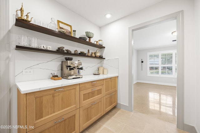 bar with decorative backsplash, light tile patterned floors, and light stone counters