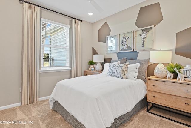 bedroom with ceiling fan, light carpet, and multiple windows