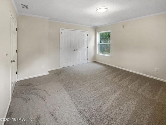 unfurnished bedroom featuring a closet, carpet floors, a textured ceiling, and ornamental molding