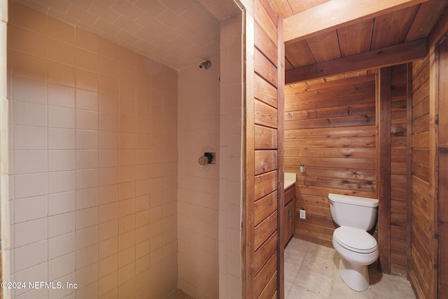 bathroom featuring vanity, wood walls, toilet, and a shower