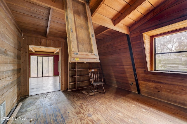 interior space featuring vaulted ceiling with beams, wooden walls, and wood ceiling