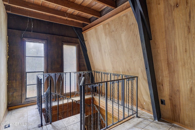 interior space featuring beam ceiling, wood walls, and wood ceiling