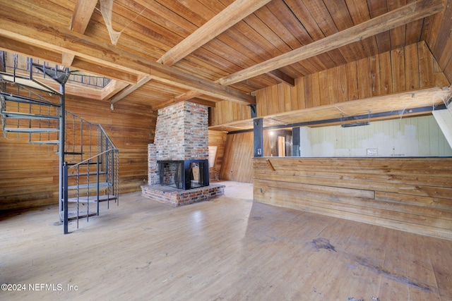 unfurnished living room featuring beamed ceiling, wooden walls, a fireplace, wood ceiling, and hardwood / wood-style flooring