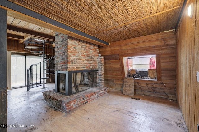 unfurnished living room featuring beamed ceiling, wood walls, wood ceiling, and a brick fireplace