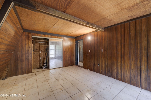 unfurnished room with wood ceiling and wooden walls