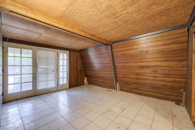 spare room with a healthy amount of sunlight, wood walls, and wooden ceiling