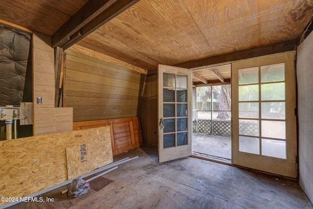 unfurnished room featuring beam ceiling, wooden walls, french doors, and wood ceiling