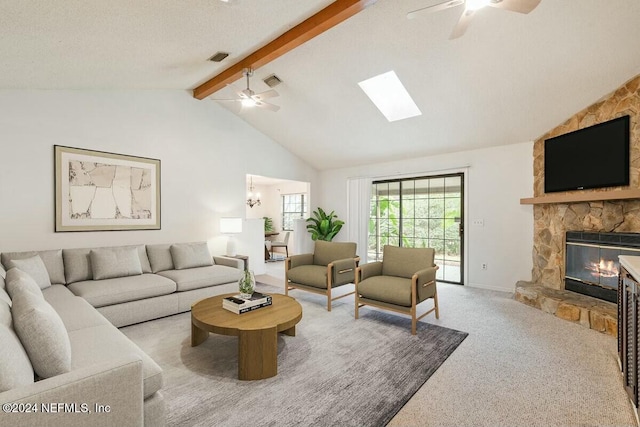 living room with ceiling fan, lofted ceiling with skylight, a textured ceiling, a fireplace, and carpet