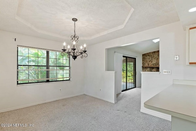 unfurnished dining area featuring a raised ceiling, light carpet, a healthy amount of sunlight, and a notable chandelier