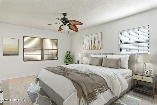 bedroom featuring ceiling fan, light colored carpet, and a textured ceiling