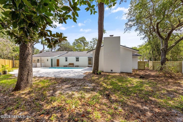 back of house with a fenced in pool and a patio area