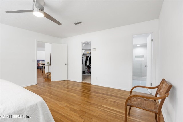 bedroom with a spacious closet, ceiling fan, ensuite bathroom, a closet, and hardwood / wood-style flooring