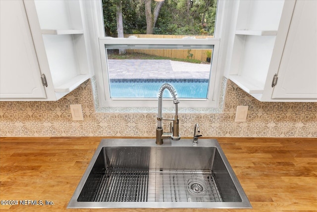 kitchen with white cabinets, tasteful backsplash, light hardwood / wood-style flooring, and sink