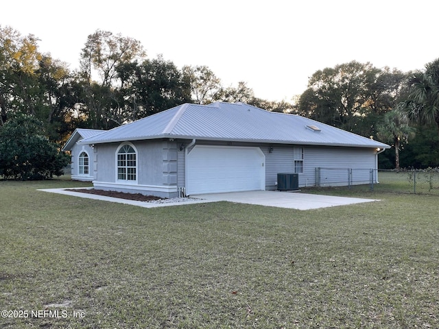 back of property featuring a garage, central air condition unit, and a lawn