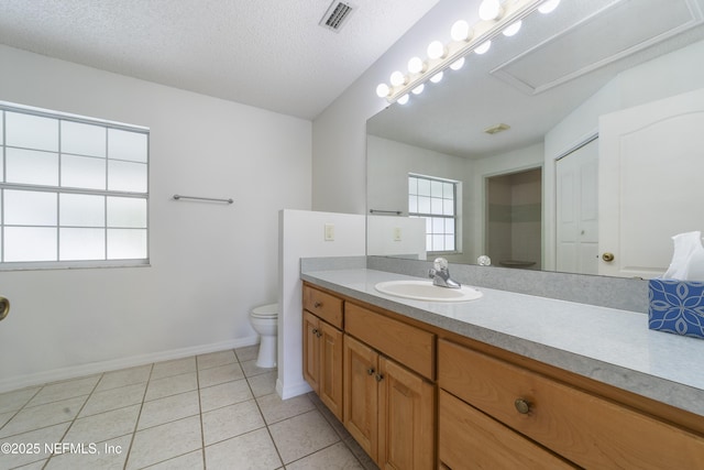 bathroom featuring toilet, vanity, tile patterned floors, and a textured ceiling