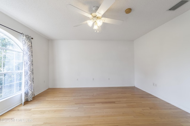 empty room with ceiling fan, a textured ceiling, and light wood-type flooring