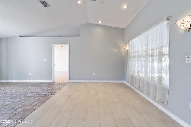 spare room with vaulted ceiling and a textured ceiling