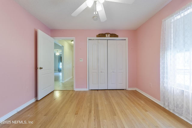 unfurnished bedroom featuring ceiling fan, a closet, and light hardwood / wood-style flooring