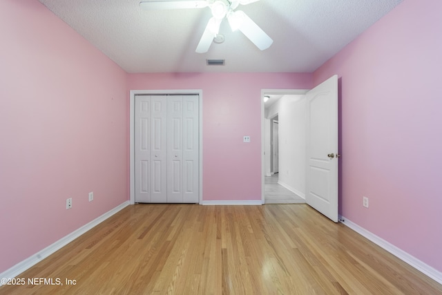 unfurnished bedroom with ceiling fan, a textured ceiling, a closet, and light hardwood / wood-style flooring