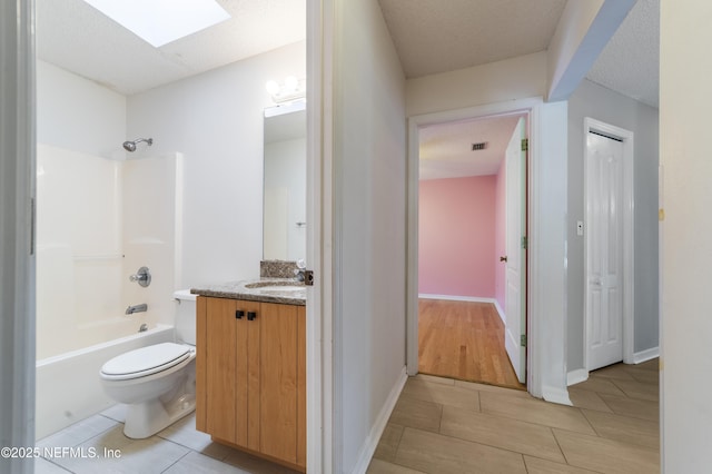 full bathroom featuring a textured ceiling, shower / tub combination, vanity, a skylight, and toilet