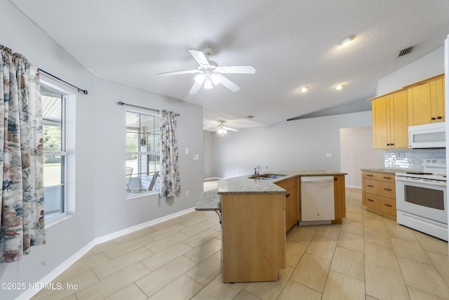 kitchen featuring light brown cabinets, backsplash, white appliances, vaulted ceiling, and sink