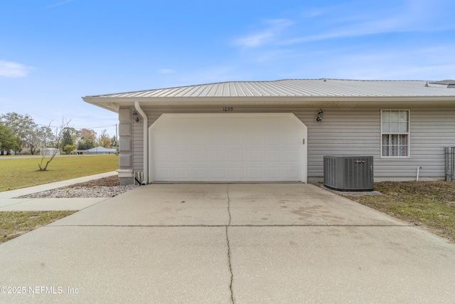 garage with a lawn and central AC unit