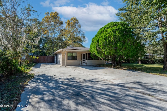 view of front facade featuring concrete driveway and fence