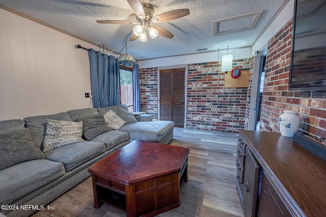 living area with ornamental molding, a textured ceiling, brick wall, and wood finished floors