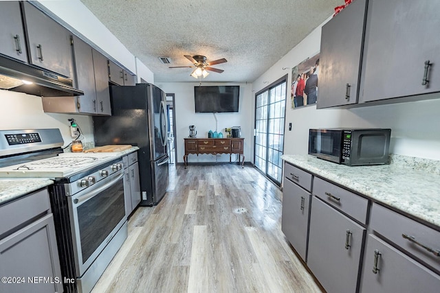 kitchen with under cabinet range hood, visible vents, light countertops, light wood-type flooring, and black appliances