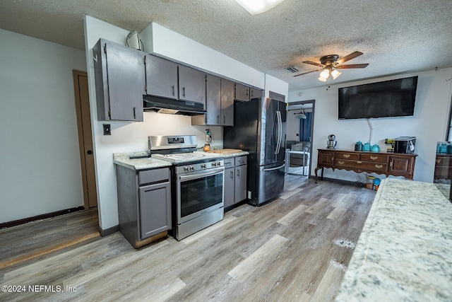 kitchen with light wood-style flooring, under cabinet range hood, visible vents, light countertops, and appliances with stainless steel finishes