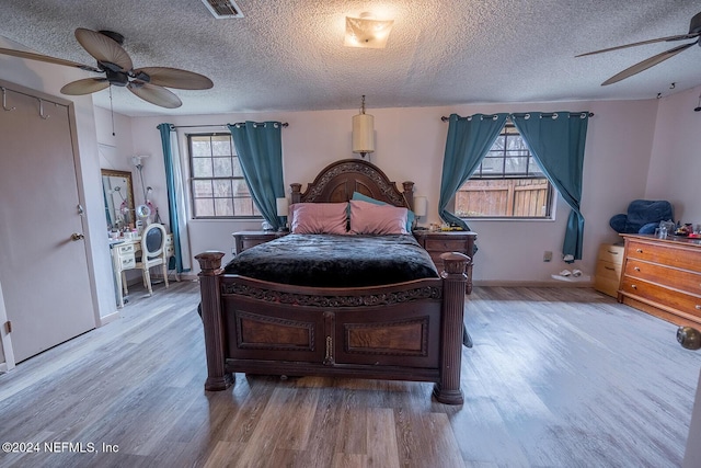 bedroom featuring a textured ceiling, wood finished floors, visible vents, a ceiling fan, and baseboards