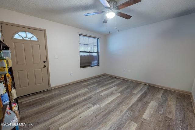 entrance foyer featuring a textured ceiling, baseboards, and light wood-style floors