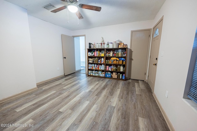 unfurnished room featuring a textured ceiling, a ceiling fan, baseboards, visible vents, and light wood-style floors