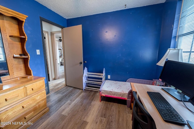 bedroom with a textured ceiling and wood finished floors