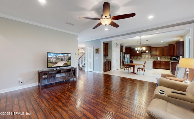 living room with crown molding, dark hardwood / wood-style floors, and ceiling fan with notable chandelier