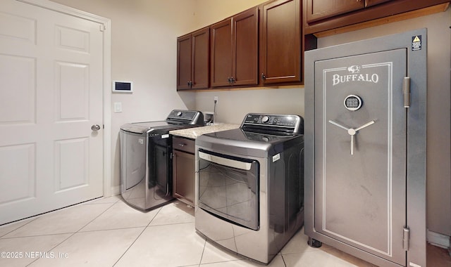 laundry area with washer and clothes dryer, cabinets, and light tile patterned floors